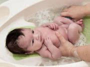 Младенца купают в ванночке